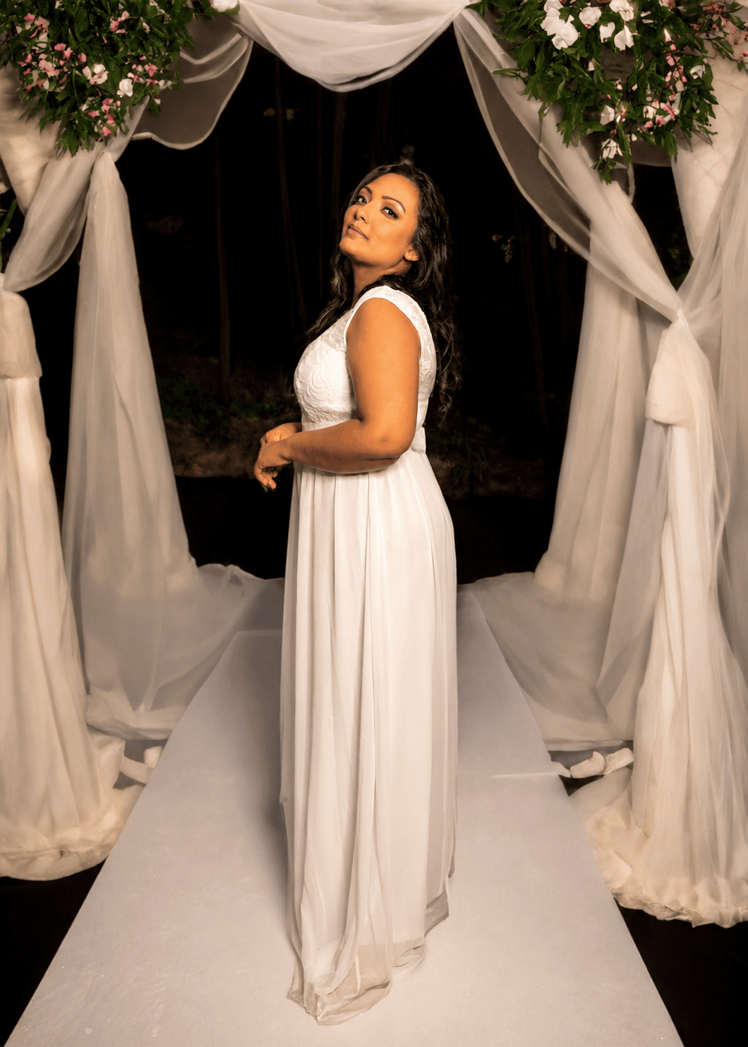 Bride seated beneath a floral wedding arch — MZ Photographer Wedding Photography